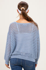 woman wearing a light blue open-knit maternity sweater, viewed from the back, paired with jeans