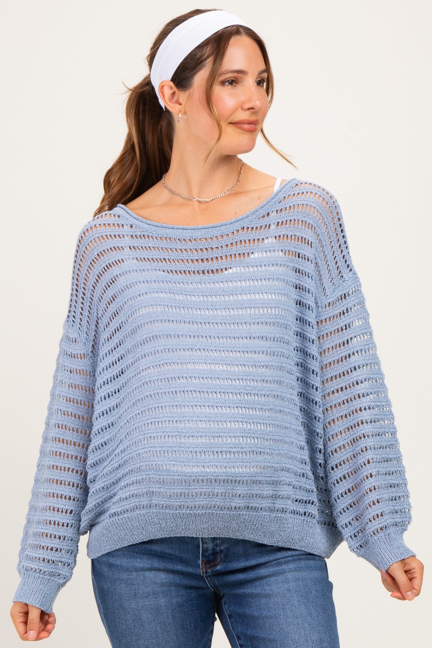 woman wearing a light blue open knit maternity sweater with a relaxed fit and long sleeves, smiling with a headband