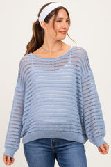 woman wearing a light blue open knit maternity sweater with a relaxed fit and long sleeves, smiling with a headband