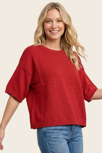 woman wearing a bright red oversized short sleeve sweater and smiling at the camera