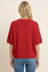 woman wearing a red short sleeve knit sweater, viewed from the back, paired with blue jeans