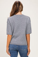 woman wearing a gray short sleeve maternity sweater, styled with a relaxed fit and ribbed hem, viewed from the back