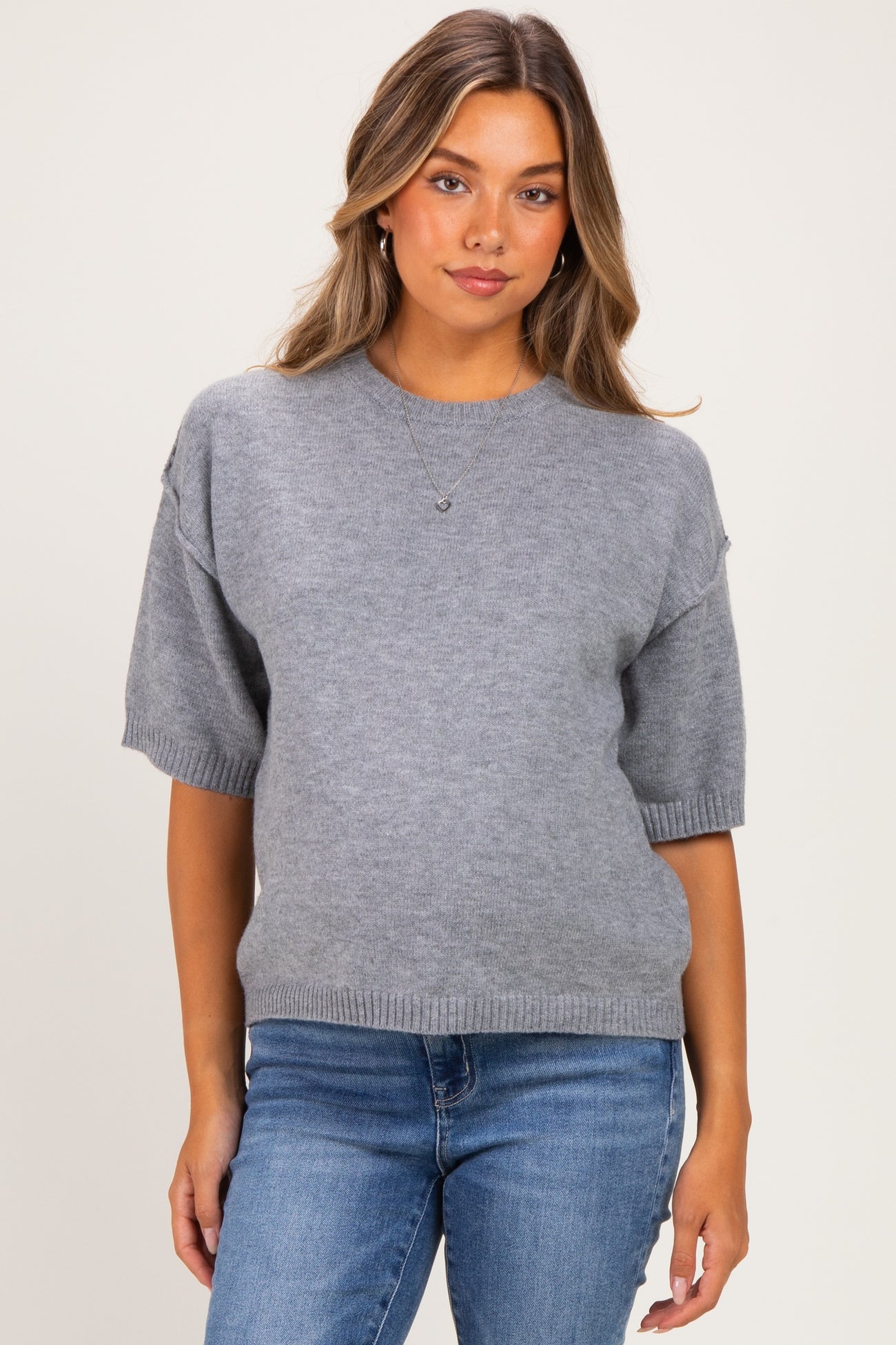 woman wearing a gray short sleeve maternity sweater and blue jeans