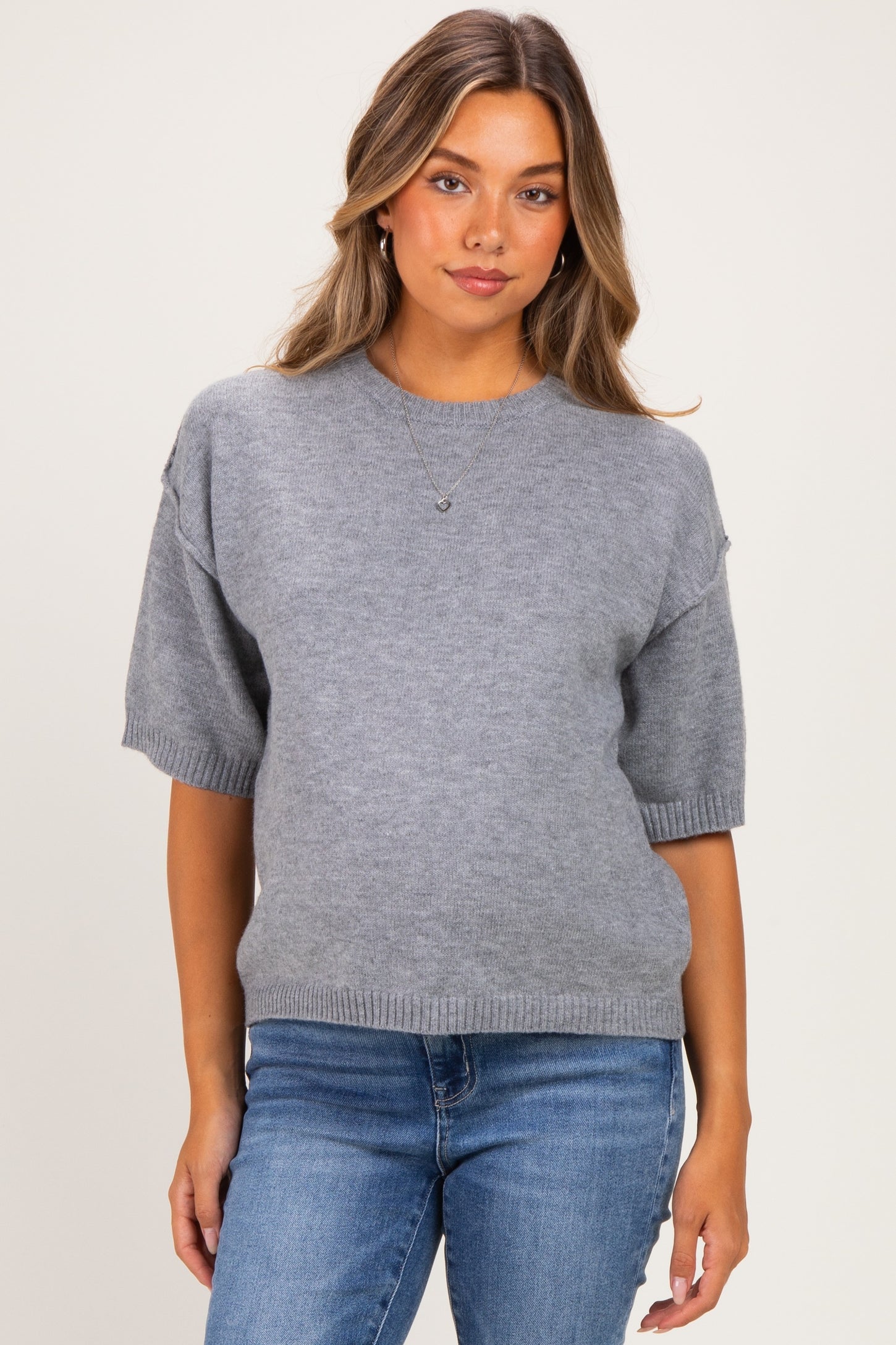 woman wearing a gray short sleeve maternity sweater and blue jeans