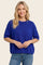 woman wearing a vibrant blue short sleeve sweater paired with light blue jeans