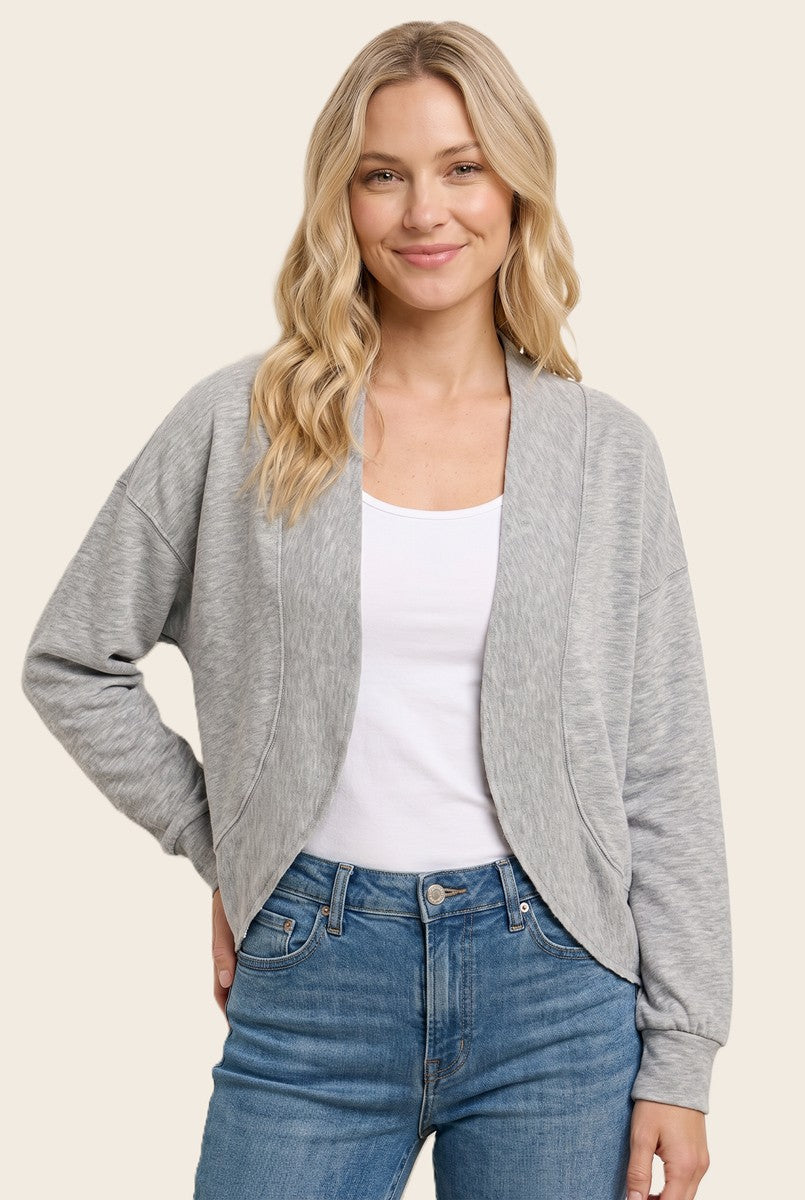 woman wearing a light gray cropped cardigan over a white tank top and blue jeans