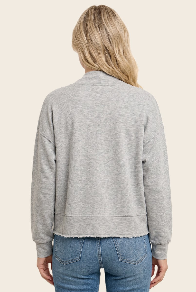 woman wearing a light gray cropped sweatshirt with a raw hem, styled with blue jeans