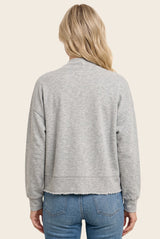 woman wearing a light gray cropped sweatshirt with a raw hem, styled with blue jeans