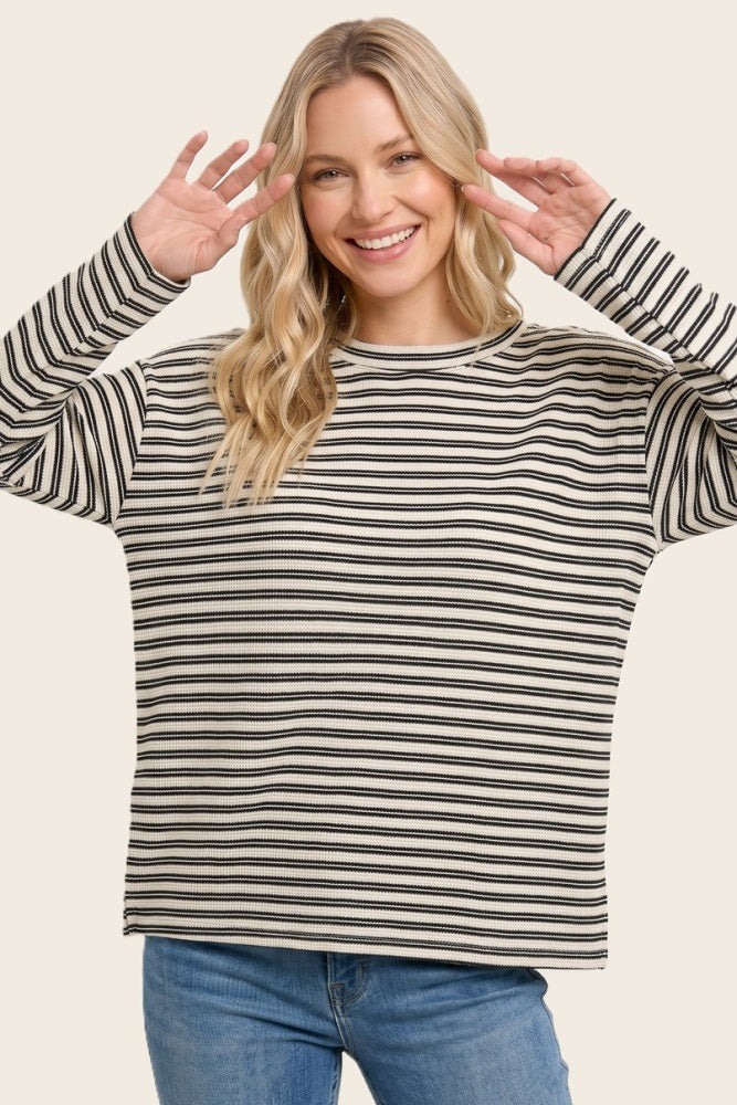 woman wearing a black and white striped oversized sweater and smiling with hands up