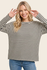 woman wearing a black and white striped oversized sweater and smiling with hands up