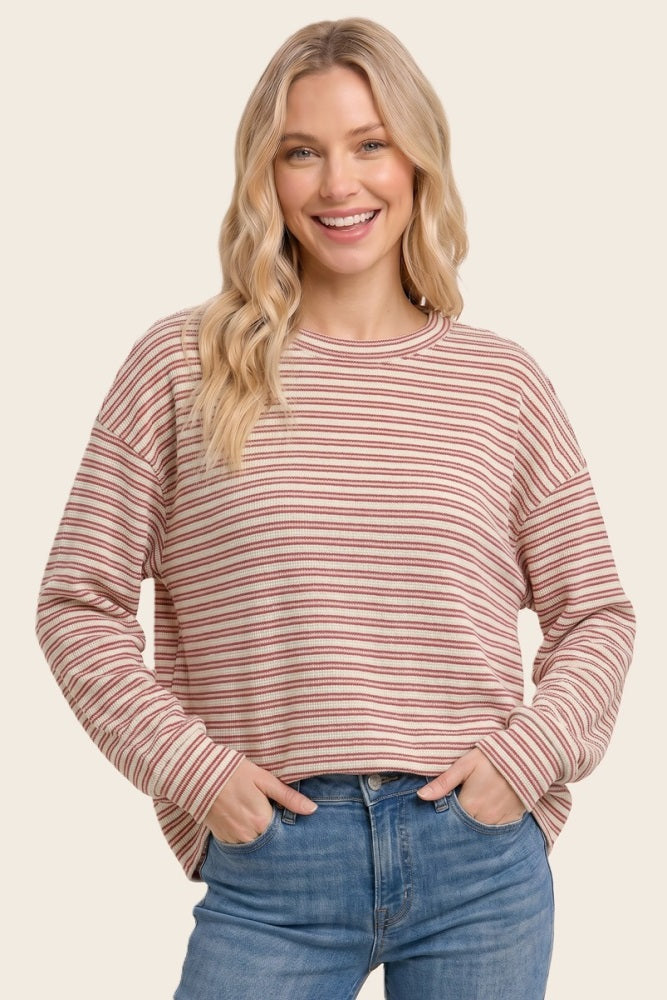 woman wearing a striped long sleeve oversized top in pastel colors with a relaxed fit and a round neckline