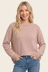 woman wearing a striped long sleeve oversized top in pastel colors with a relaxed fit and a round neckline