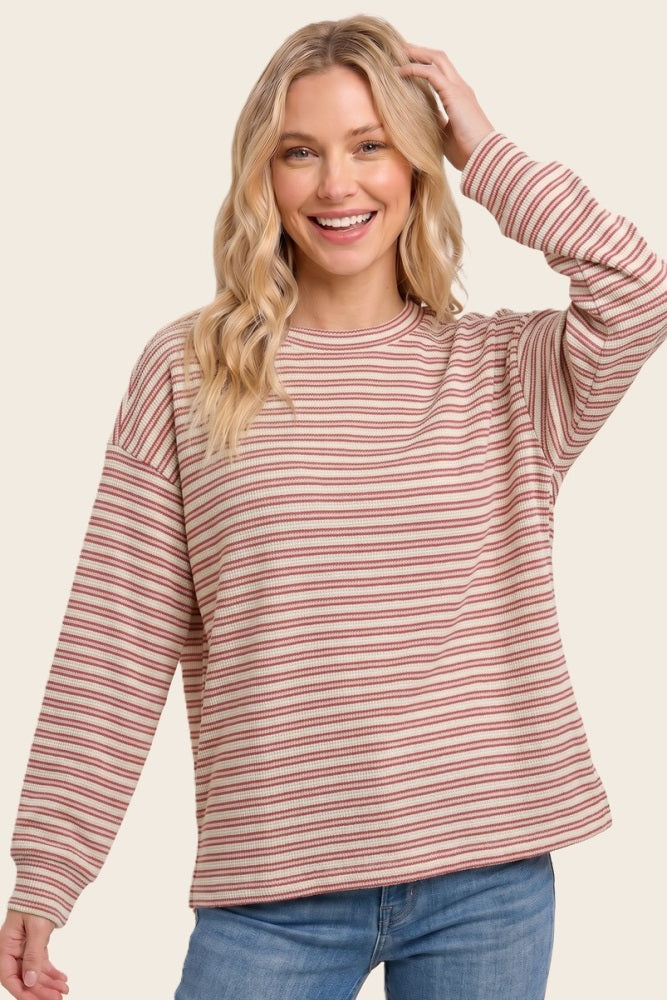 woman wearing a red and cream striped long sleeve sweater with relaxed fit and rounded neckline