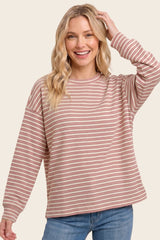 woman wearing a red and cream striped long sleeve sweater with relaxed fit and rounded neckline