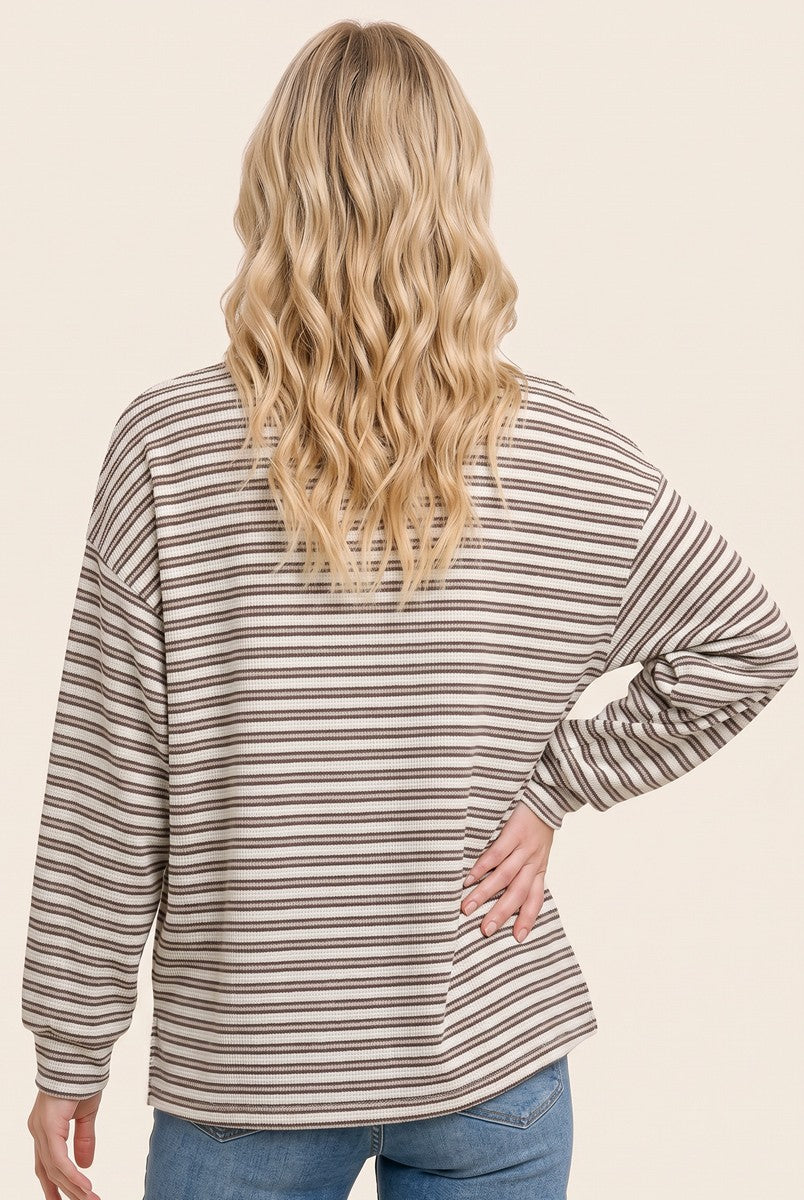 woman wearing a beige and brown striped long sleeve top, seen from the back with loose fit and relaxed style