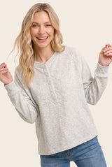 woman wearing a light gray long sleeve button-up top with a relaxed fit and round neckline