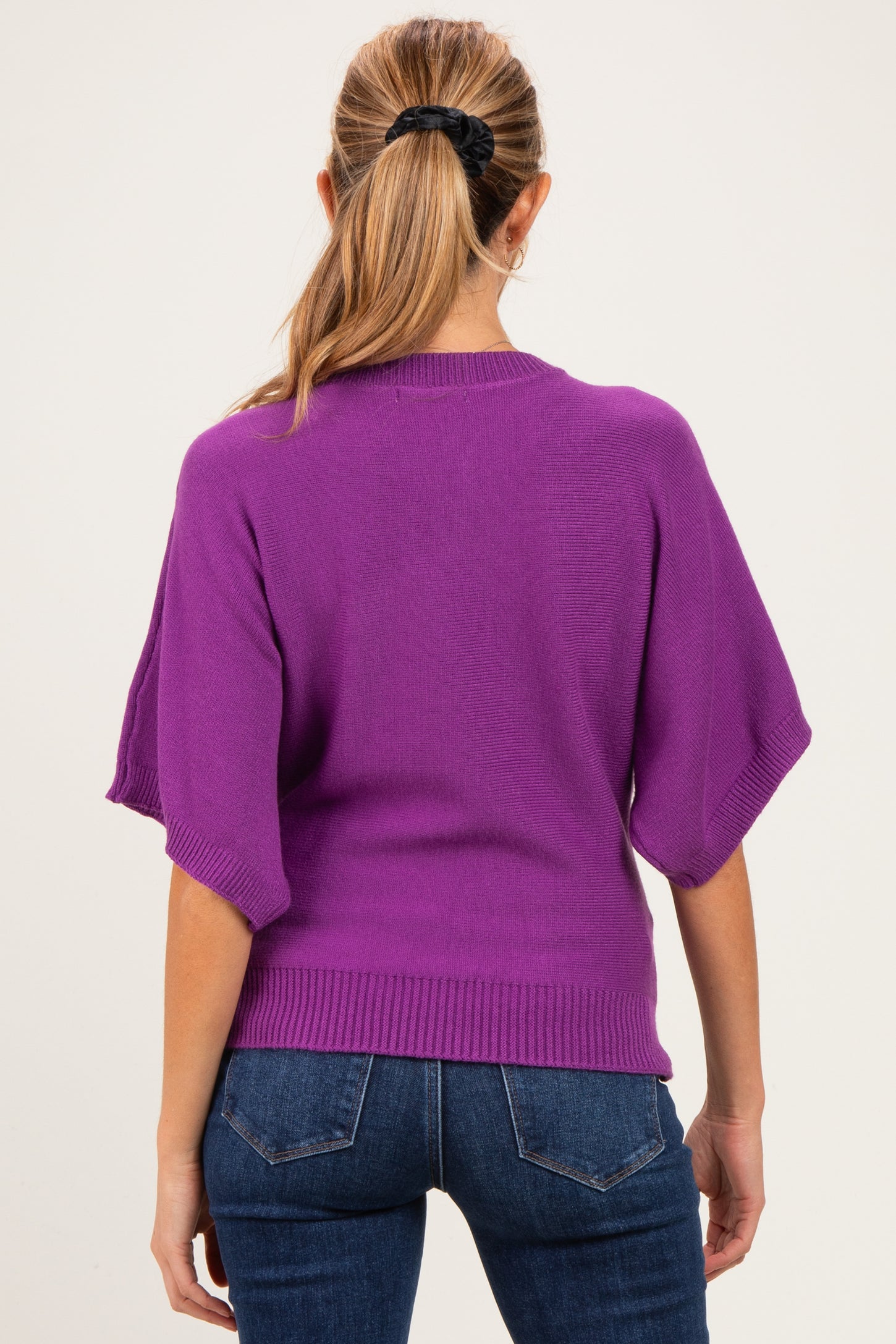 woman wearing a purple maternity sweater with wide sleeves and a relaxed fit, showing her back