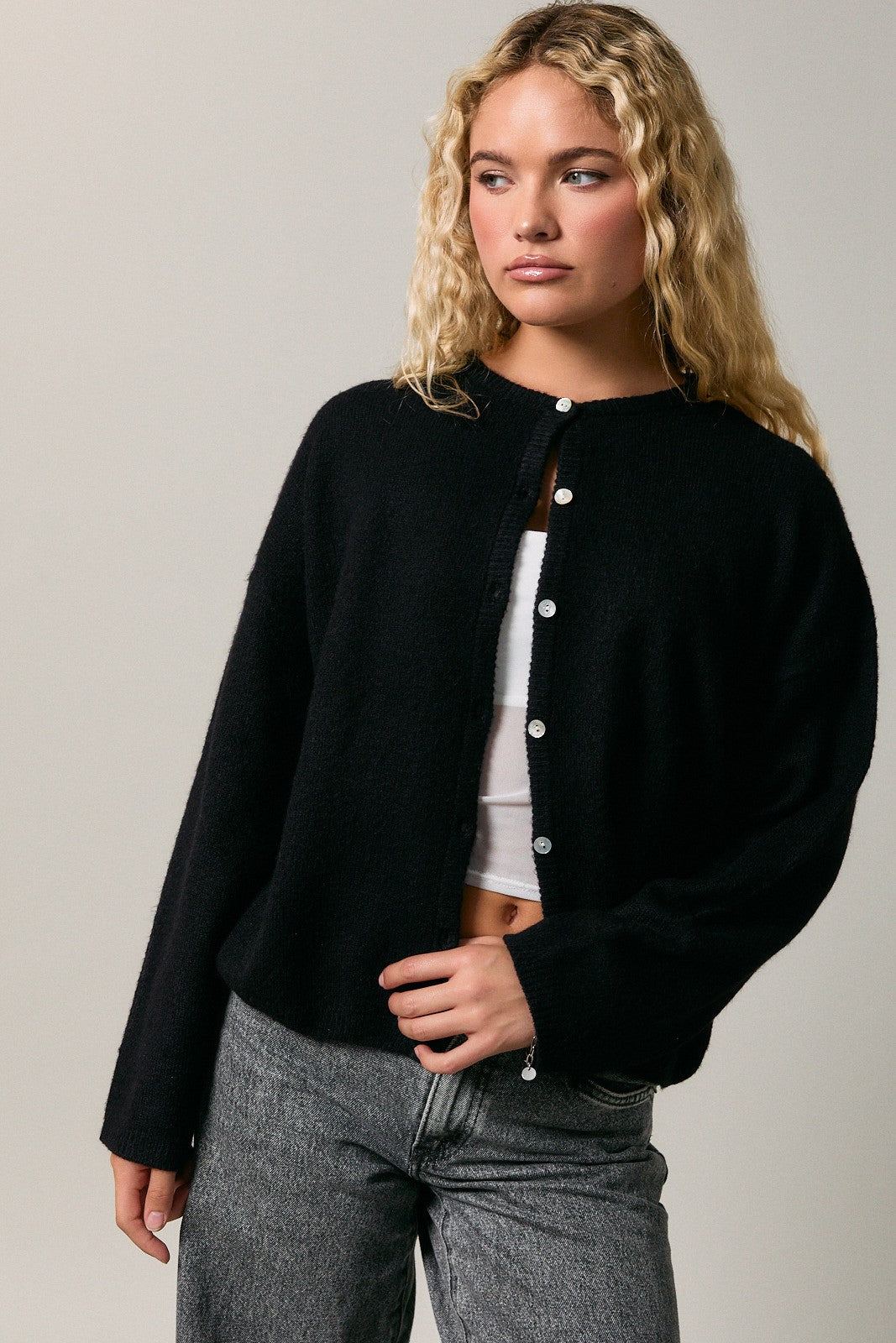 woman wearing a black oversized cardigan with buttons and gray high-waisted jeans