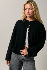 woman wearing a black oversized cardigan with buttons and gray high-waisted jeans
