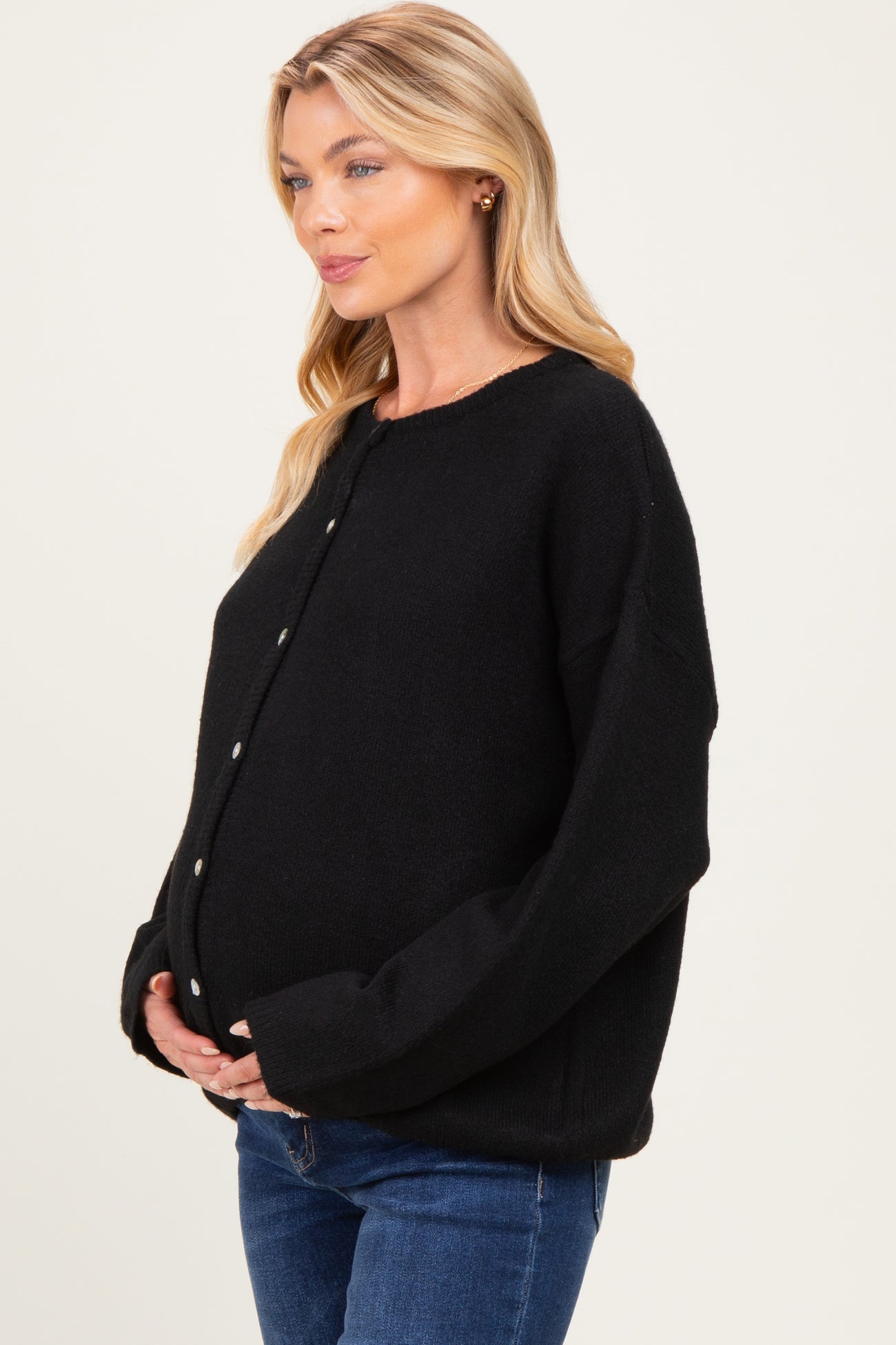 woman wearing a black oversized cardigan and showing her baby bump