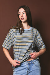woman wearing a gray striped oversized t-shirt with blue accents and high-waisted denim jeans