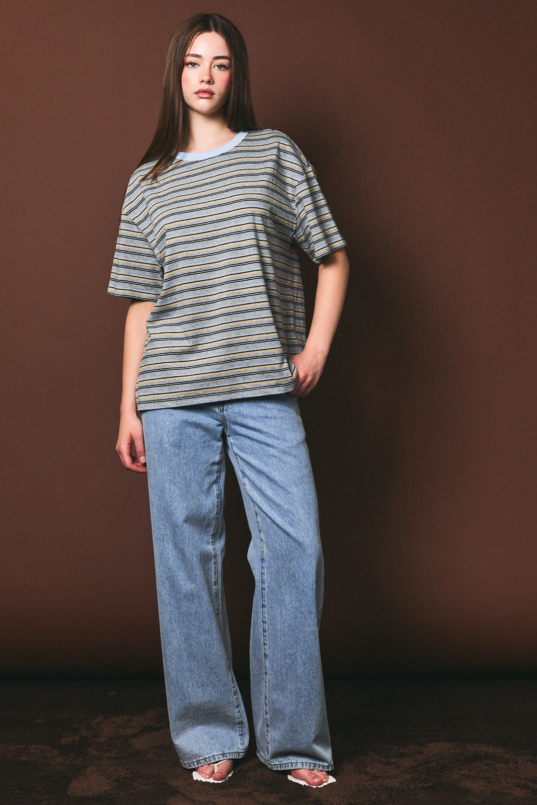 woman wearing a gray and blue striped oversized t-shirt and light blue wide-leg jeans