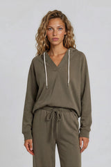 woman wearing an olive green hoodie with a v-neck and drawstring, styled with matching joggers
