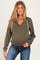 woman wearing an olive green maternity hoodie with a v-neck and drawstring detail, paired with blue jeans