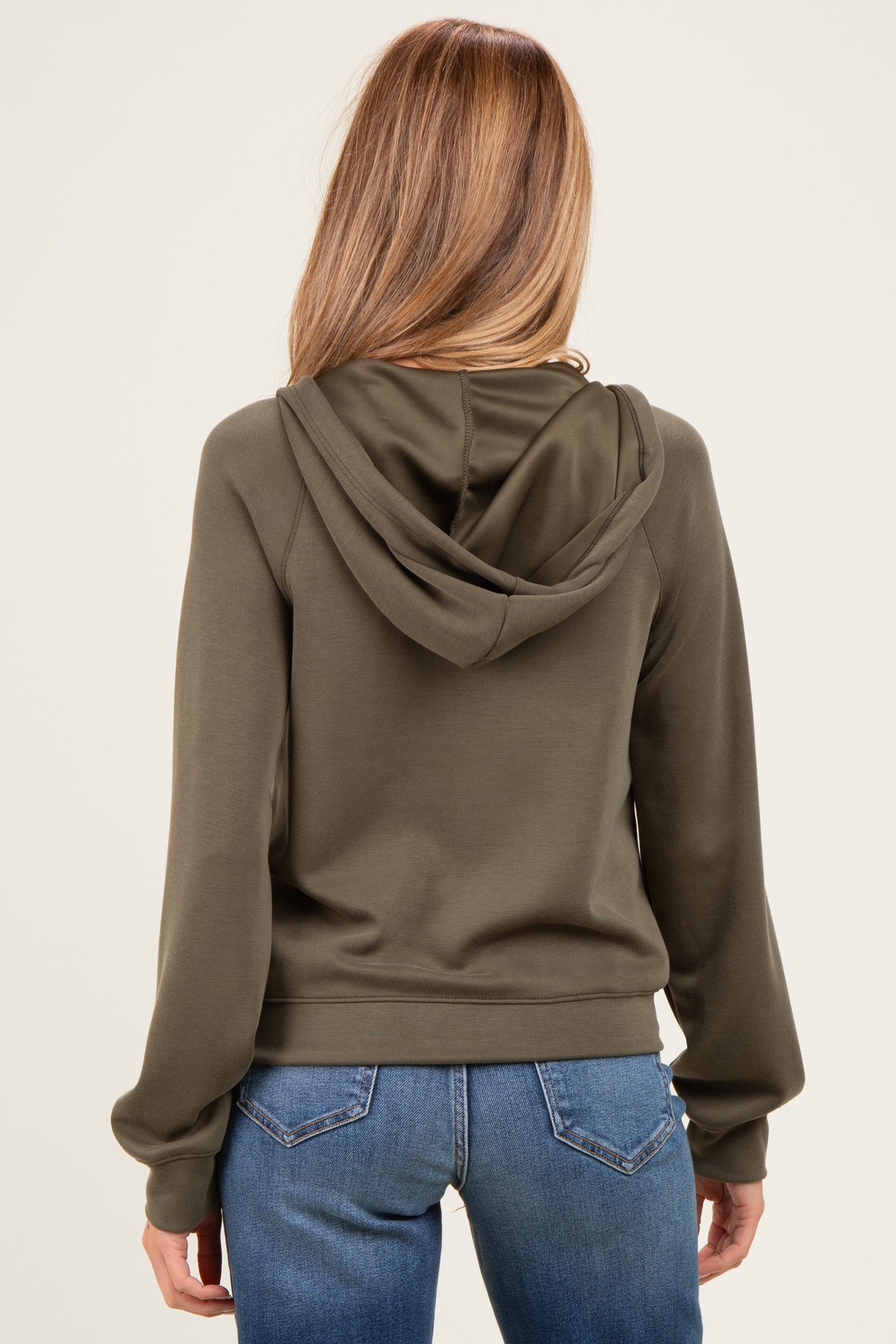 woman wearing a green maternity hoodie with a relaxed fit and back view, paired with blue jeans