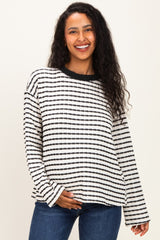 woman wearing a striped black and white maternity sweater with long sleeves and a relaxed fit, holding her baby bump