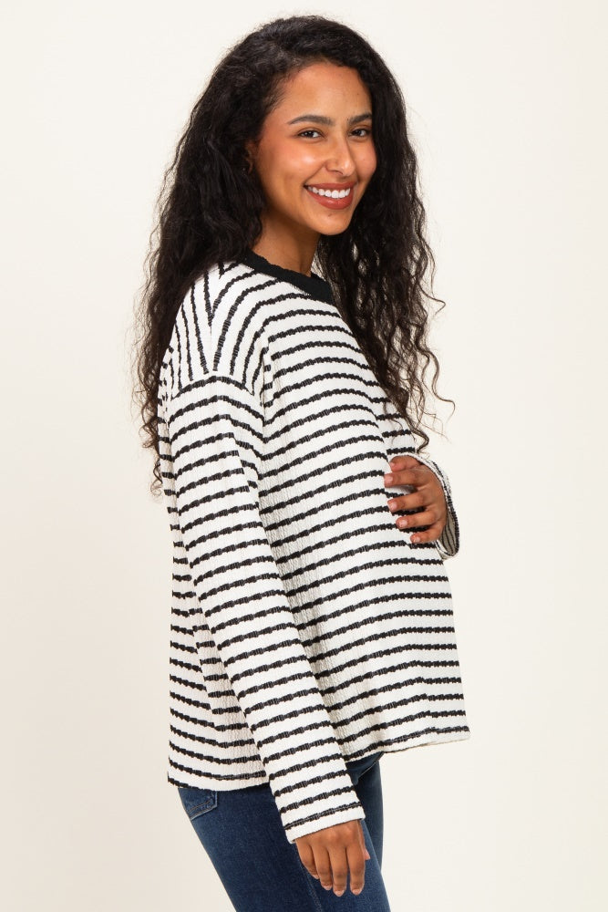 woman wearing a black and white striped maternity sweater and holding her baby bump