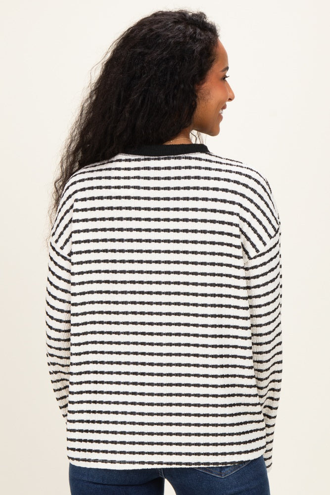 woman wearing a black and white striped maternity sweater, shown from the back with curly hair and no visible baby bump