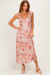 woman wearing a floral maxi dress with ruffled sleeves and a fitted bodice in shades of pink and peach
