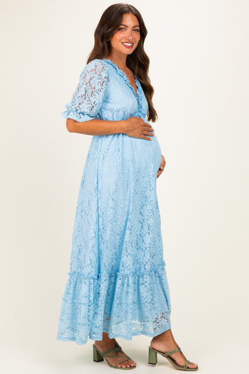 woman wearing a light blue lace maternity dress with short sleeves and a ruffled hem, showing her baby bump