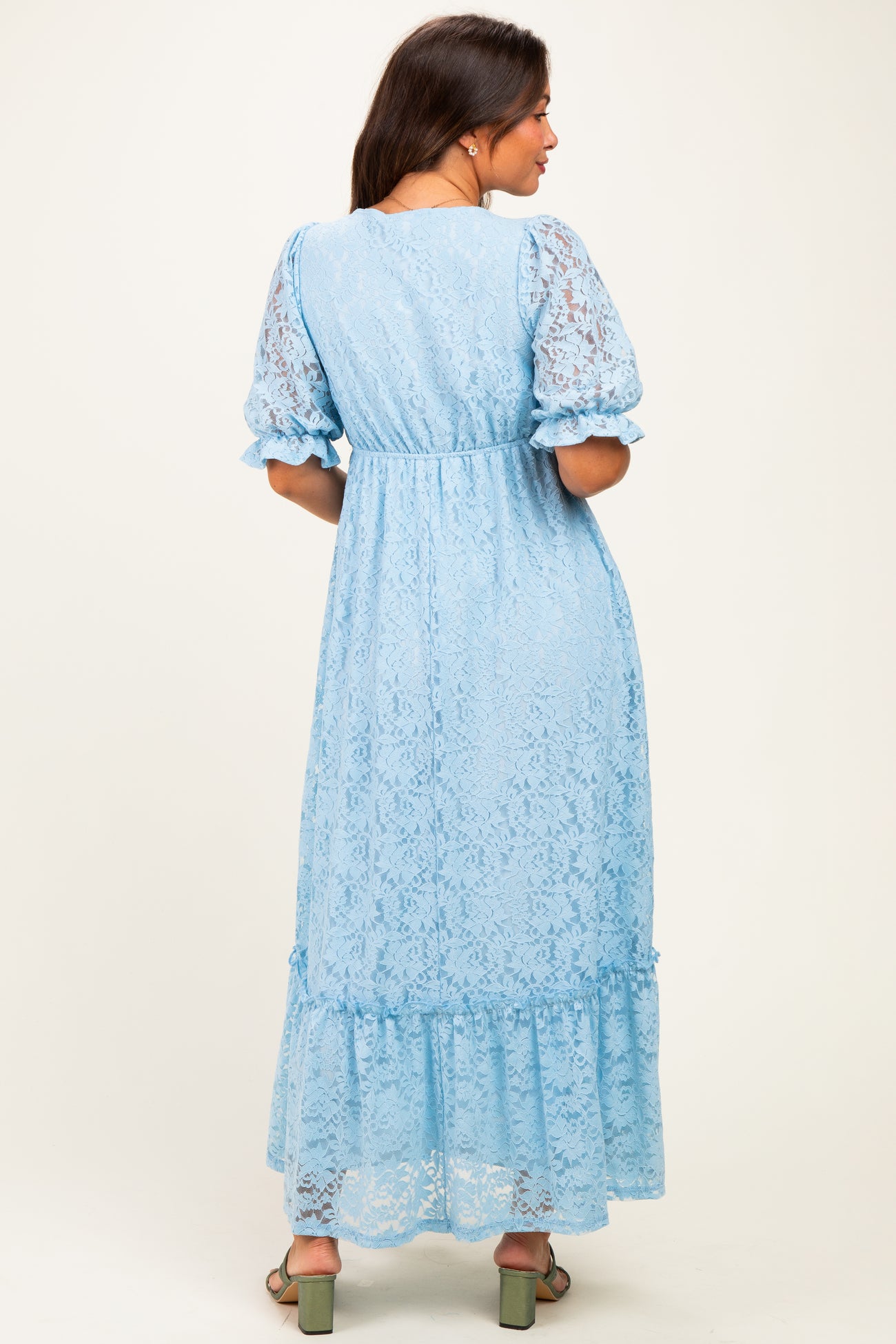 woman wearing a light blue lace maternity maxi dress with puff sleeves and a tiered hem, showing her baby bump subtly