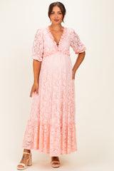 woman wearing a pink lace maternity maxi dress with a deep V-neck and ruffled sleeves, showcasing her baby bump