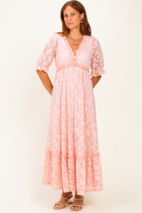 woman wearing a pink lace maxi dress with a v-neckline and puff sleeves