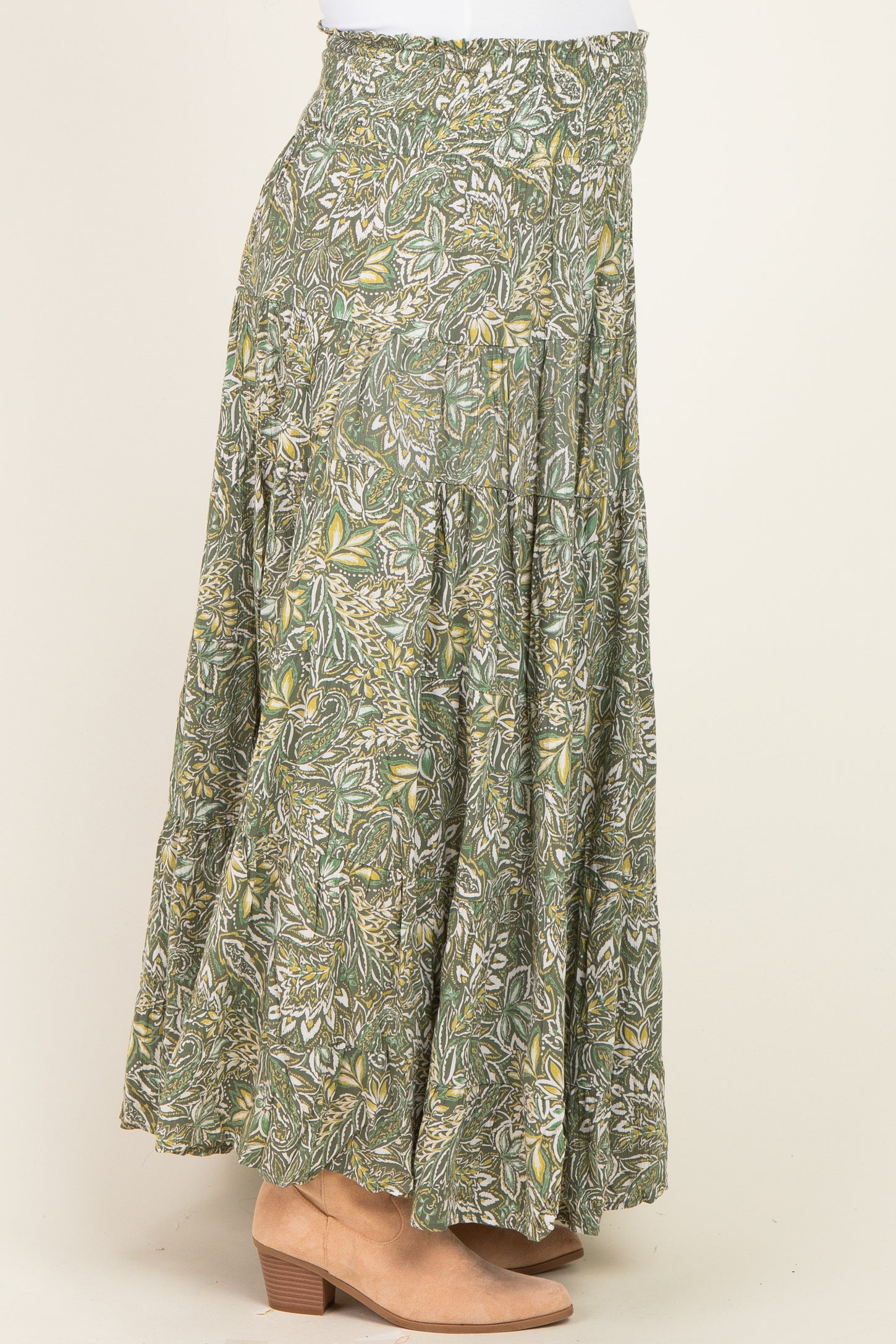 maternity wear in a green floral maxi skirt with a tiered design, worn by a model paired with tan ankle boots