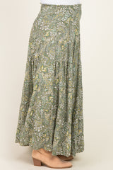 maternity wear in a green floral maxi skirt with a tiered design, worn by a model paired with tan ankle boots