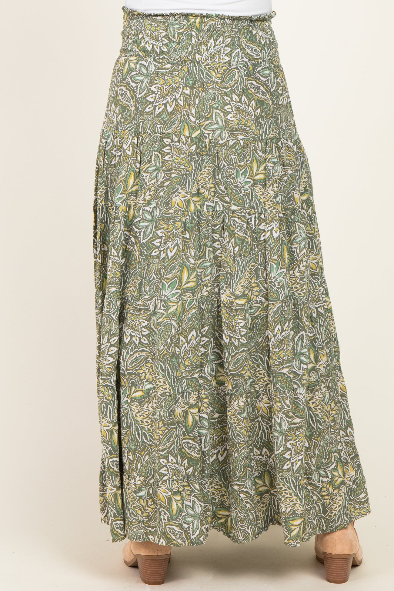 woman wearing a green floral maternity maxi skirt with a flowy design, showcasing a gathered waistband and tiered style