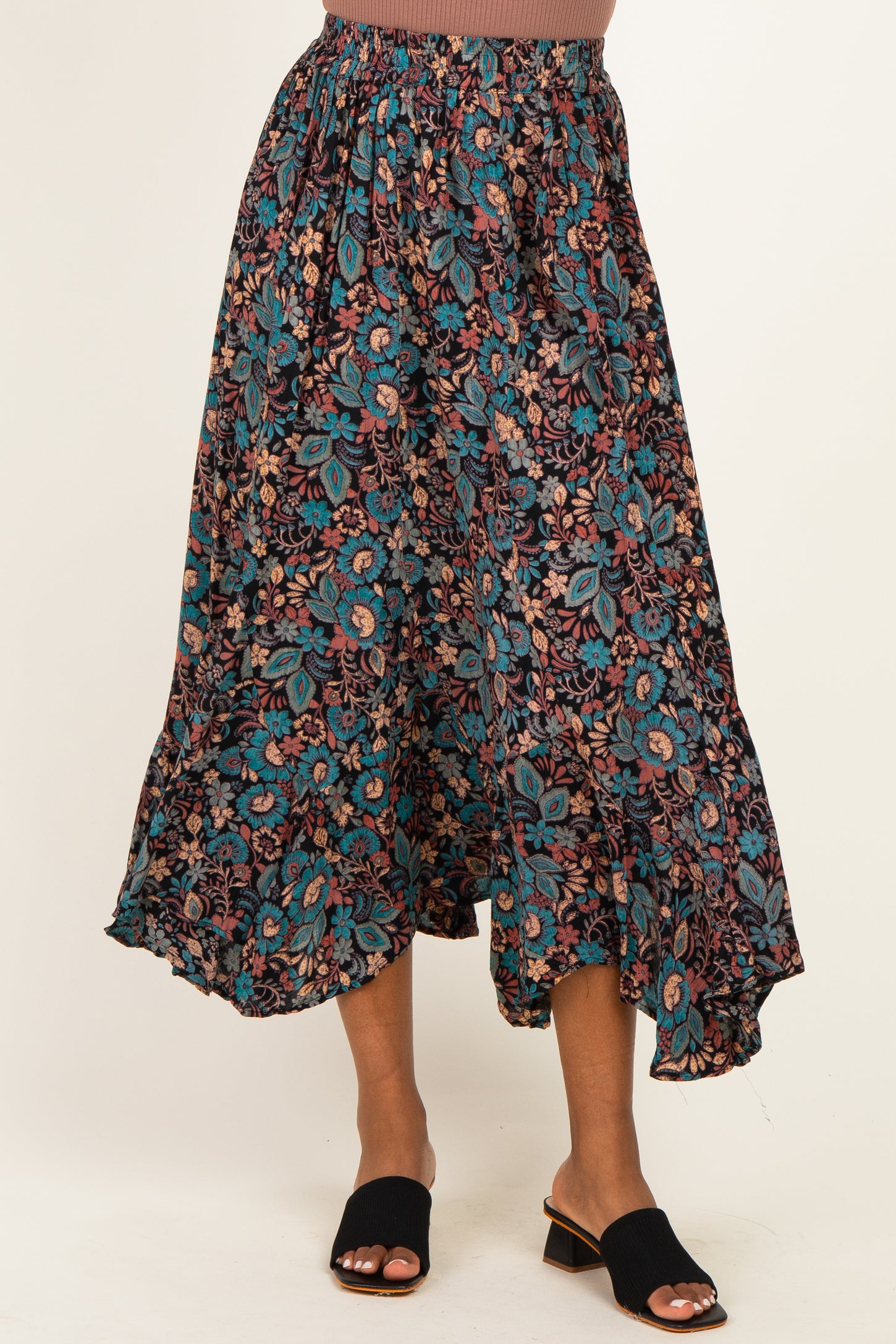 woman wearing a black floral maxi skirt with a tiered hem and elastic waistband, paired with black slide sandals