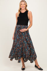 woman wearing a black sleeveless top and a floral print maternity maxi skirt, gently holding her baby bump