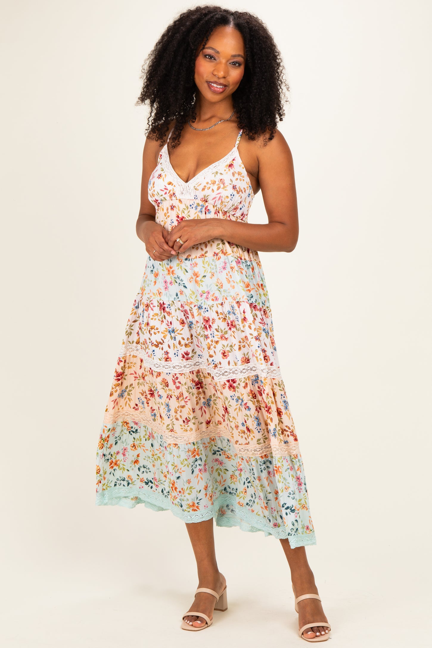 woman wearing a floral patterned sleeveless midi dress with a relaxed fit and tiered skirt, standing against a light background