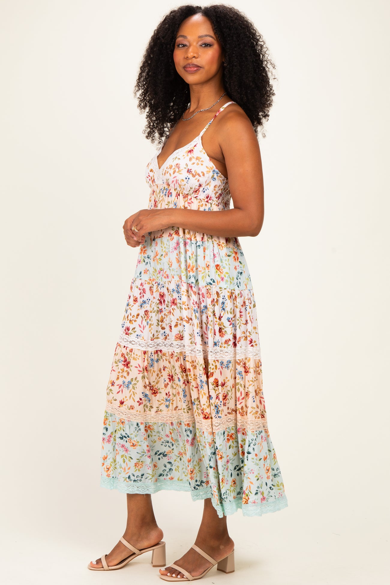 woman wearing a floral midi dress with adjustable straps and tiered layers in pastel colors