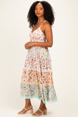 woman wearing a floral midi dress with adjustable straps and tiered layers in pastel colors