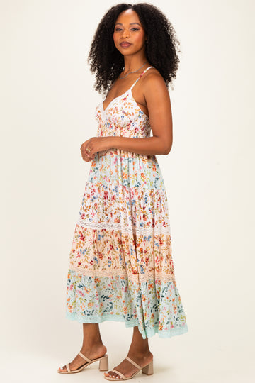 woman wearing a floral midi dress with adjustable straps and tiered layers in pastel colors