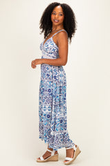 woman wearing a blue and white patterned maxi dress with a fitted bodice and flowy skirt, standing sideways