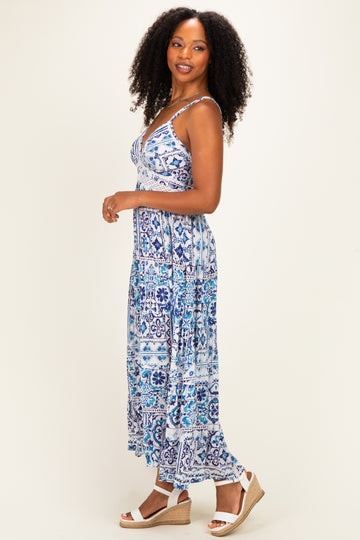 woman wearing a blue and white patterned maxi dress with a fitted bodice and flowy skirt, standing sideways