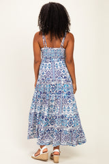 woman wearing a back view of a blue and white printed maxi dress with adjustable straps and a tiered skirt