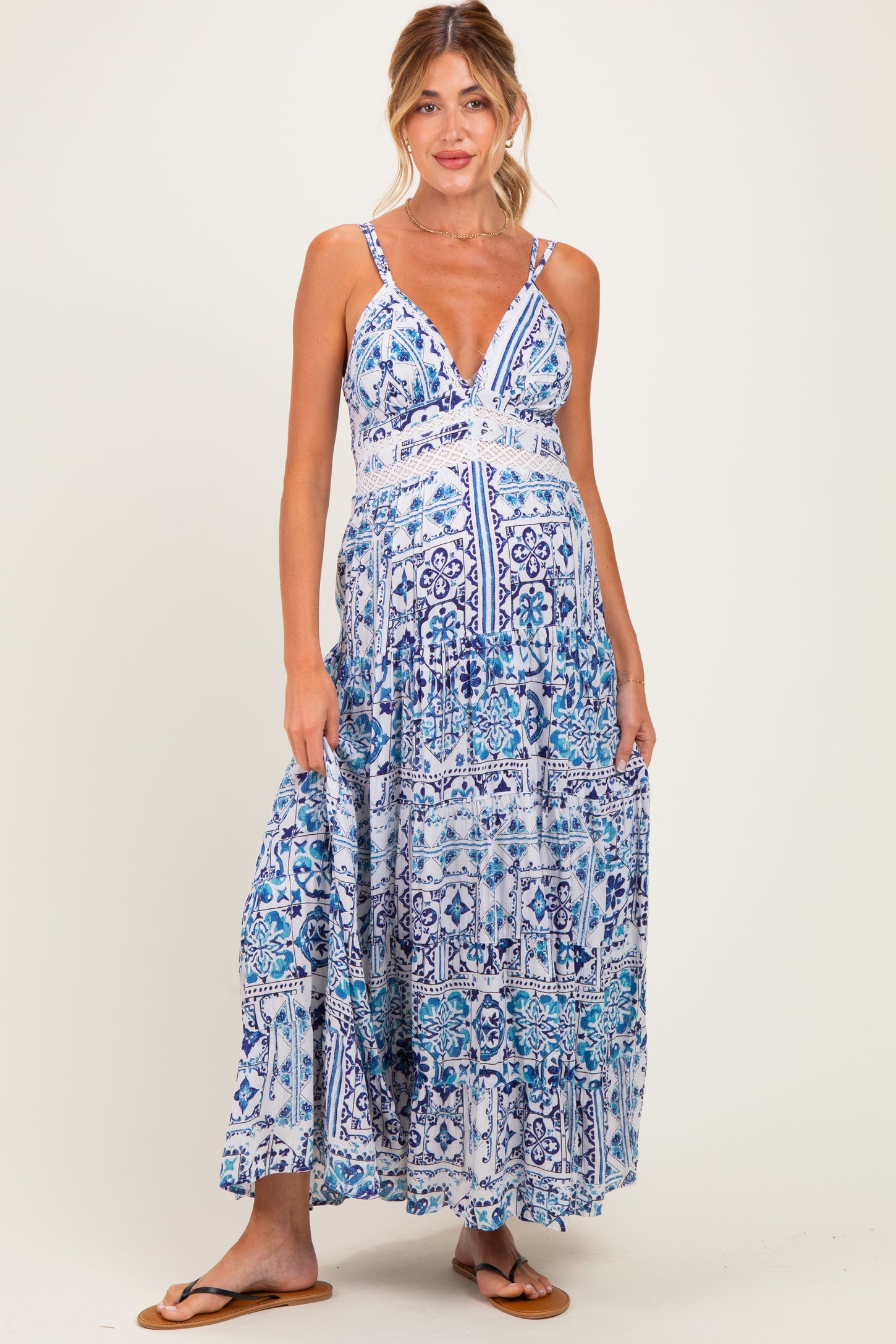 woman wearing a blue and white patterned maternity maxi dress with a deep v-neck and adjustable straps, showcasing her baby bump